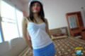 Pim standing beside bed wearing strappy top