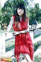 Standing against fence wearing red dress long hair over her shoulders
