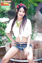 Seated on edge of wooden tub wearing knotted shirt in shorts legs open