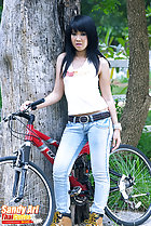 Standing under tree with bike wearing jeans