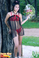 Standing against tree wearing transparent negligee holding cage